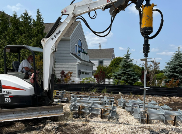 Helical pile installed with a Bobcat drive head, house behind