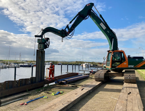 Excavator handling sheet piles at a marina