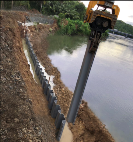 Vibratory hammer driving a sheet pile beside a river